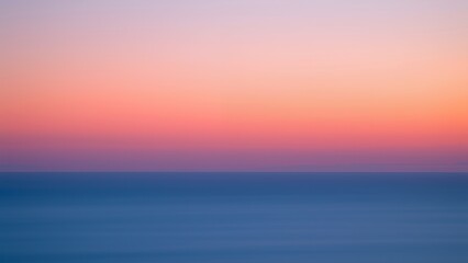 A peaceful, soft sunset over calm ocean water.