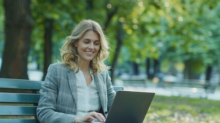Smiling businesswoman using a laptop on a park bench, enjoying the outdoors