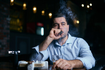 portrait of hansome man smoking cigar in a lounge bar