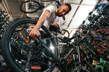 Adjusting the wheel. Repair man in bicycle shop, working in store