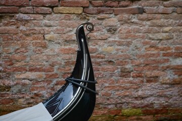 Close-up of a gondola's prow against a brick wall in Venice