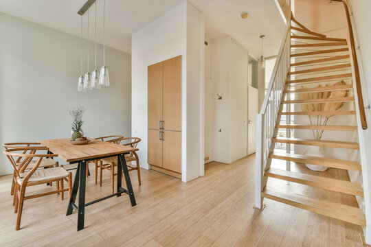 Modern dining area with wooden staircase and furniture