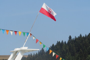 Flaga Polski umocowana na statku razem z kolorowymi trójkątami 