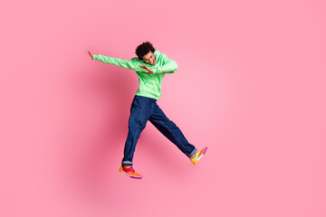 Full size photo of nice young man jump headphones empty space wear green hoodie isolated on pink color background