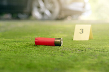 Evidence regarding firearms, Pistol bullet shell on cement floor with blurred number one on yellow...