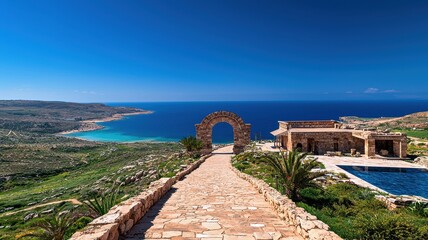 Scenic coastal view featuring a stone pathway, vibrant greenery, and azure waters under a clear blue sky.