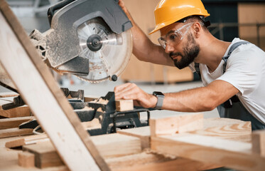 Side view, cutting the wood. Industrial worker in the warehouse