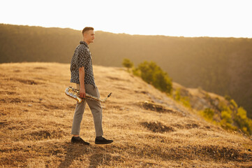 A musician stands with a trumpet against a beautiful sunset landscape, capturing a moment of...