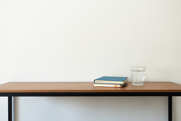 Planner and glass of water on wooden desk. Morning routine habit, minimal