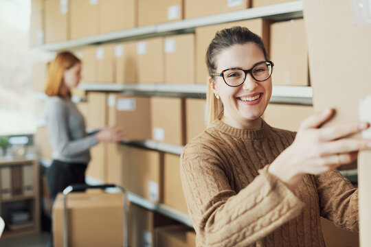 Happy e-commerce employee moving boxes in the warehouse