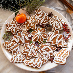 Baking sweets for Christmas holidays at home. Gingerbread baked at home oven and painted with sugar glazing. Symbolic shapes of Christmas trees and snowflakes. Traditional food for december season.