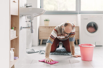 Frustrated man cleaning the wet floor in the bathroom