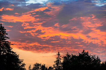 Orange glowing evening clouds in the sky above the Brunnenbach in the forest near Augsburg...