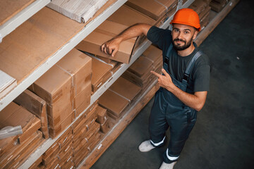 Looking up, standing. Foreman is in the storehouse, shipping distribution business