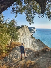 A man stands at the edge of Corfu’s dramatic cliffs, admiring the stunning view of the rugged coastline
