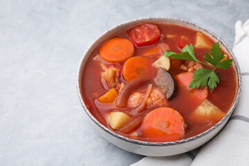 Delicious homemade stew in bowl on light table, closeup