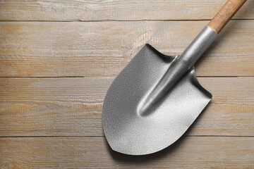 Metal shovel on wooden table, top view. Space for text