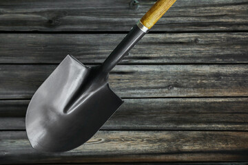Metal shovel on black wooden surface, top view