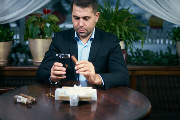 Man lights a cigar while sitting in a restaurant