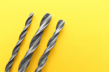 Different drill bits on yellow background, top view. Space for text