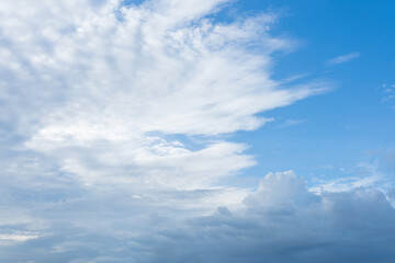Fluffy white clouds drift across a bright blue sky, painting a beautiful summer day