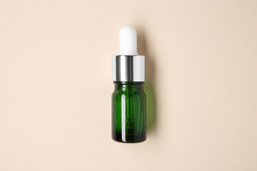 Essential oils in bottle on beige background, top view