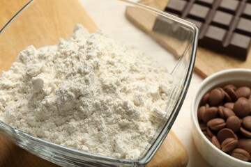 Flour in bowl and chocolate for making dough on light table, closeup