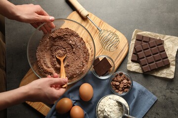 Woman making chocolate dough at grey table, top view