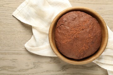 Chocolate dough in bowl on wooden table, top view