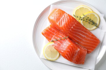 Pieces of fresh salmon with thyme and lemon on white table, top view. Space for text