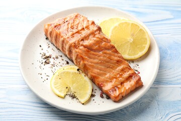 Delicious grilled salmon fillet served on light blue wooden table, closeup