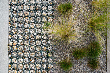 Pebbles and gravel are arranged in a geometric pattern on one side, while tufts of grass grow among...
