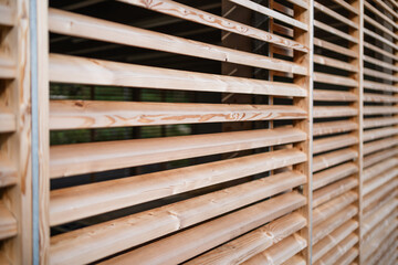 Wooden slats form a detailed, close-up view of a natural timber construction, showcasing the texture, pattern, and grain of the material, with warm brown tones and natural lighting.