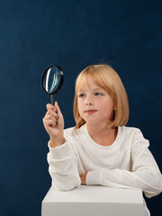 A blonde girl is photographed for a school album in a studio with a movie camera