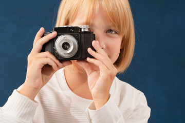 A blonde girl is photographed for a school album in a studio with a movie camera