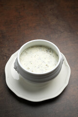 Azerbaijani Dovga soup in a white bowl, top view. Healthy soup with fermented milk and various greens