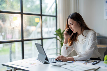 Stressed asian businesswoman receiving bad news during phone call at work