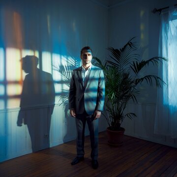 Cinematic Medium Shot of a Man Standing in a Room with Shadows