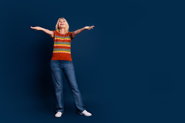 Photo of positive cheerful nice senior woman wear striped stylish clothes hold empty space isolated on dark blue color background