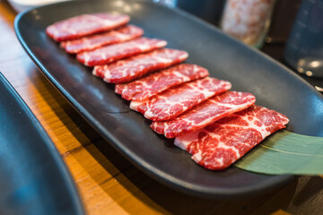 Premium fresh raw sliced Wagyu beef with marbled on black plate for grilled beef at Yakiniku restaurant background. A5 Yakiniku Wagyu beef sirloin served to Japanese barbecue grill, shabu or sukiyaki.