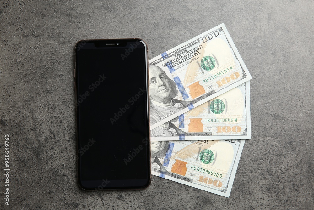 Wall mural Modern smartphone and dollar bills on grey table, top view