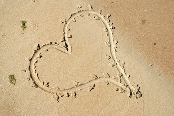 Drawing heart shape love concept on sand at the beach with vacation holiday summer travel background.