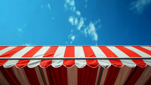 Bright red and white awning against a clear blue sky with scattered clouds during midday