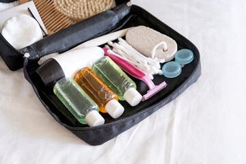 Travel cosmetics kit with bottles, brushes and cosmetics on bed