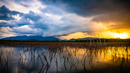 Evening sun rays with rain clouds forming over Thap Salao Dam, Uthai Thani Province, Thailand.
