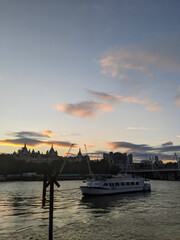 Fototapeta premium The sun set along the river Thames in central London with a boat in view.