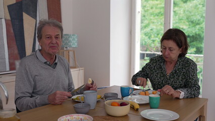 Elderly couple enjoying breakfast together, showcasing a serene morning routine and companionship at the dining table in a bright home setting