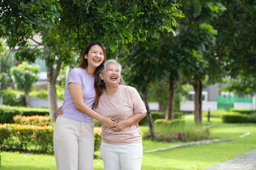 Fototapeta premium Two women are laughing and hugging in a park. Scene is happy and joyful