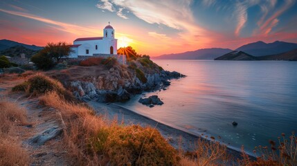 Photo of a white church with a beautiful sea view at sunset.