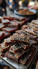 A stack of dried meat jerky seasoned with herbs and spices, displayed in a market setting. Ideal for food photography, street food promotions, or showcasing artisanal, high-protein snacks.